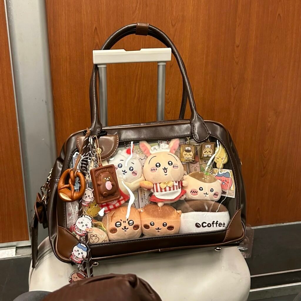 ita bag with clear window showing enamel pins, acrylic standees, and a pastel backing insert
