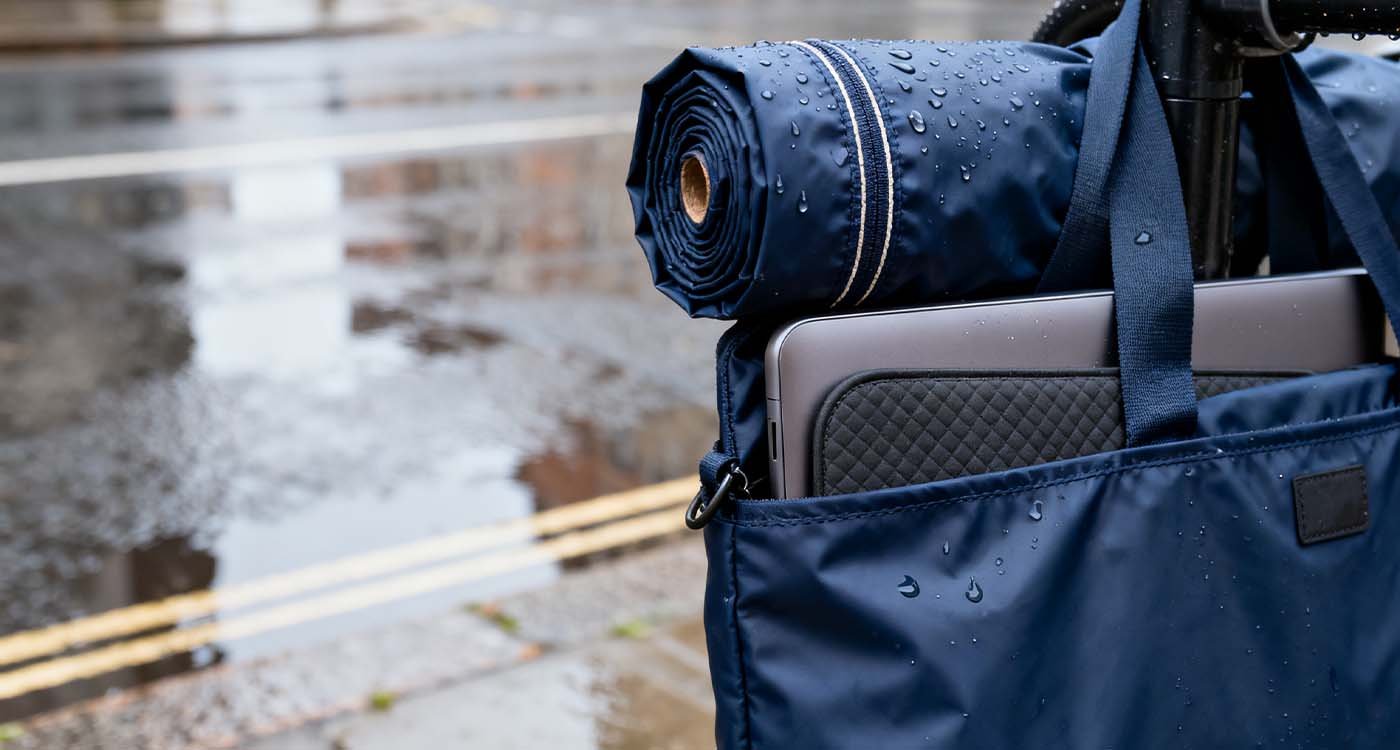 Laptop Bag Gifts For Her: How to pick a present she'll actually use - laptop bag young woman carrying a convertible tote-backpack laptop bag walking past a cafe, padded sleeve visible inside