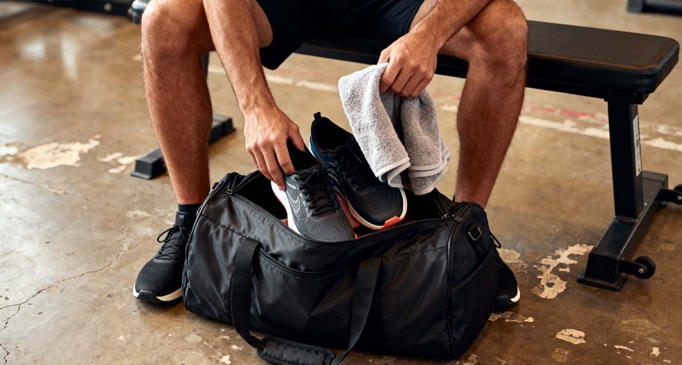 The Ultimate Gym Bag Guide: 2025 Edition - laptop bag Athlete packing black duffel gym bag before workout