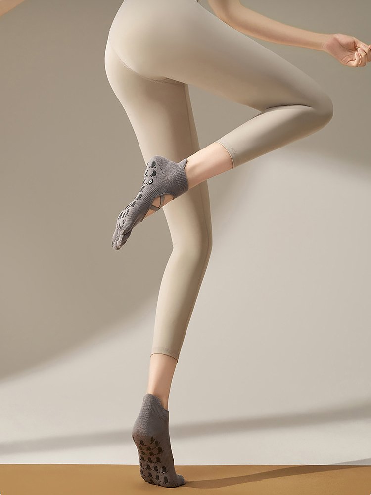 Grey Cross Strap Pilates Socks worn by a model in a fitness pose.