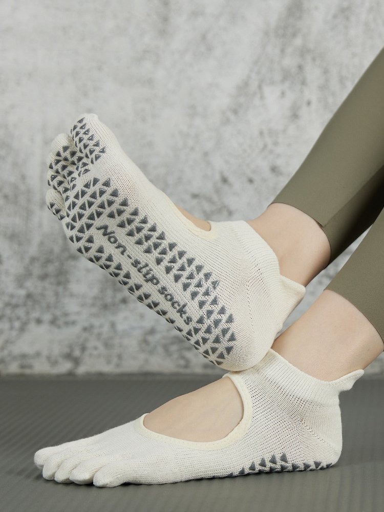 Close-up of cream five-toe Pilates socks showing triangular non-slip silicone grips.