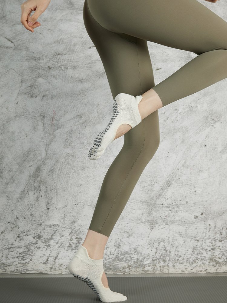 Side view of a person in motion wearing white non-slip five-toe fitness socks.