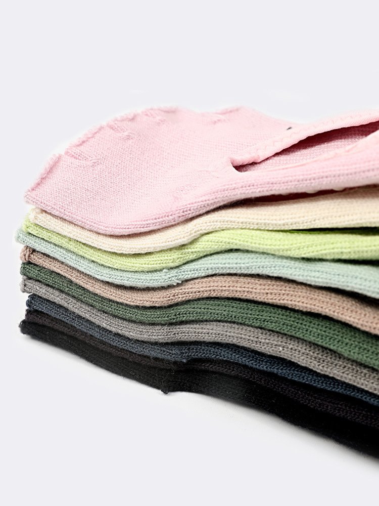 A stack of colorful Toeless Pilates Socks in various studio shades.