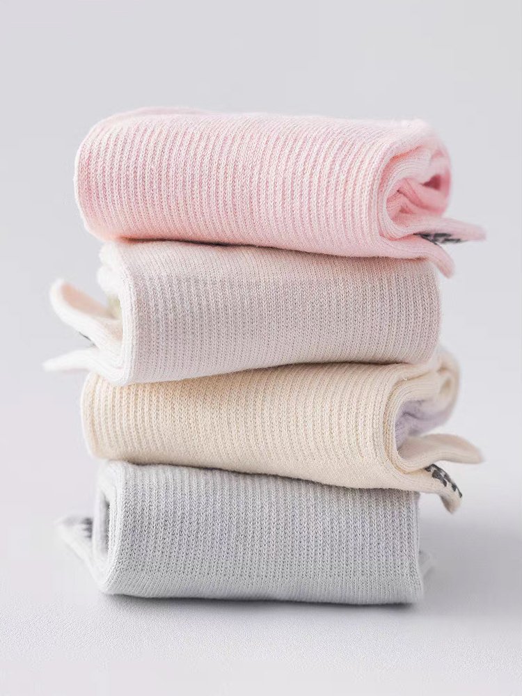 A stack of Gradient Five-Toe Pilates Socks in pink, beige, and grey.